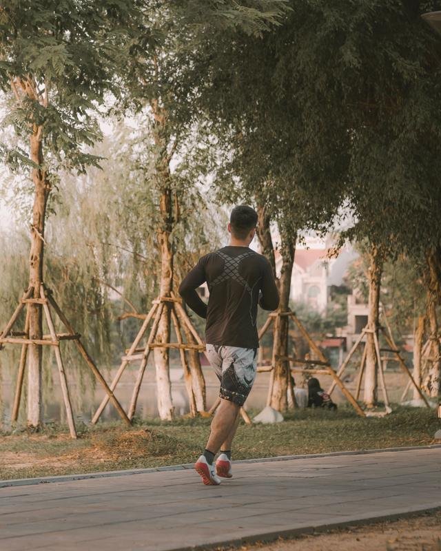 A man jogging along a tree-lined park path