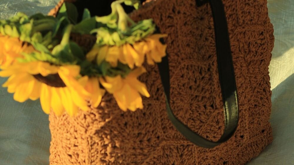 Sunflowers, a woven bag, tea and a notebook in warm sunlight